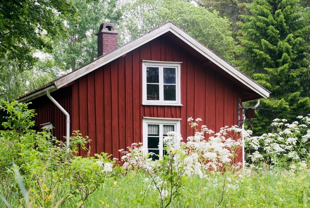 Rött hus med vita knutar i skogen